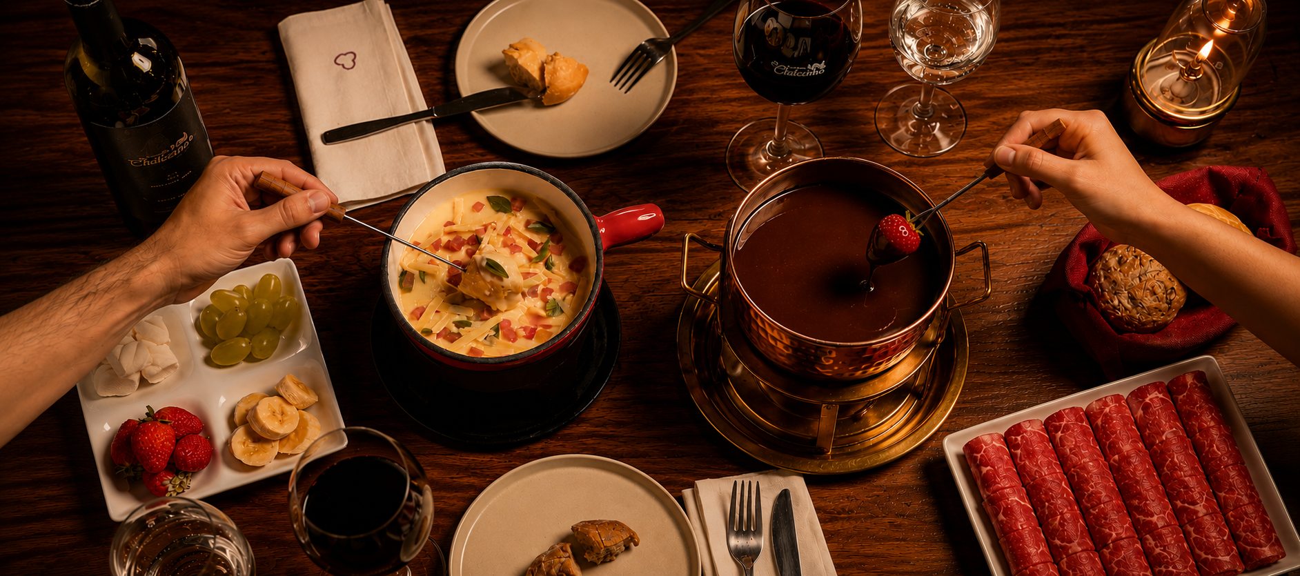 Mesa com fondue de queijo, fondue de chocolate com morango, carnes, frutas e vinho no Chalezinho
